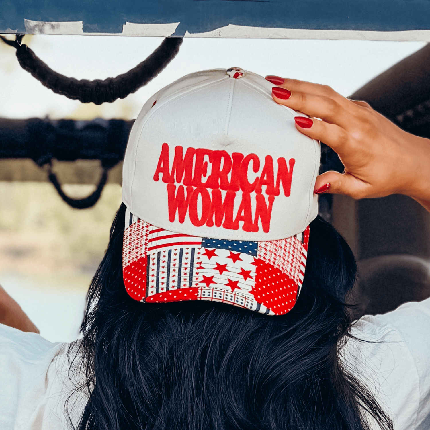 American Woman puff pattern hat with a red and white star design, worn backwards, showing the back view and hair.