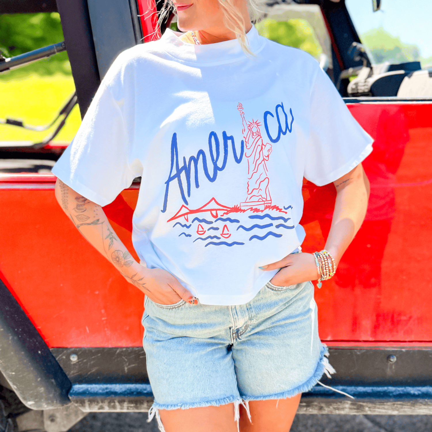 Lady Liberty relaxed boxy tee in white with red and blue graphic, featuring the Statue of Liberty and a scenic design.