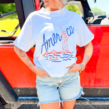 Lady Liberty relaxed boxy tee in white with red and blue graphic, featuring the Statue of Liberty and a scenic design.